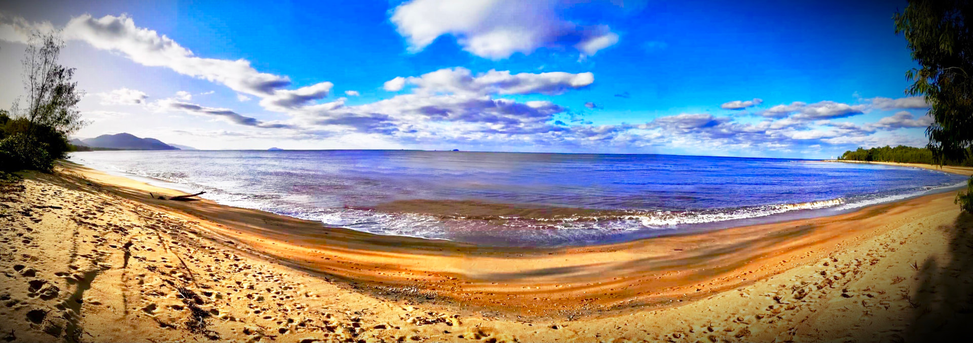 Wide panorama of Bramston Beach beneath vivid blue skies