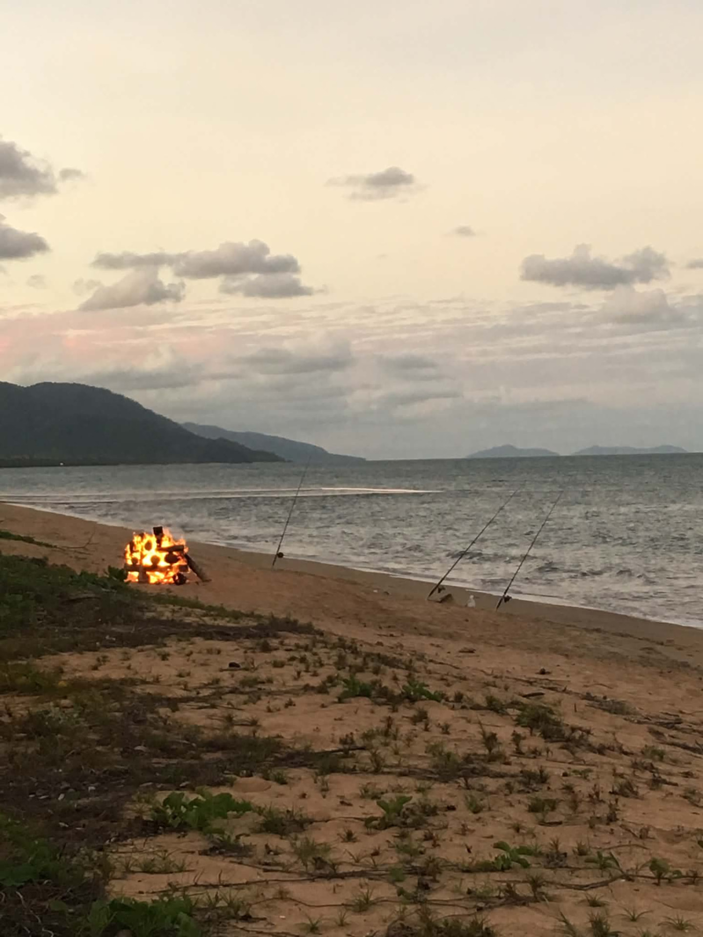 Beach bonfire with fishing rods at dusk on Bramston Beach