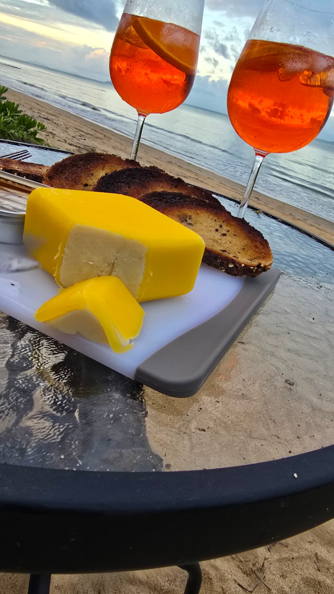 Spritz cocktails and toast on a table at the water's edge