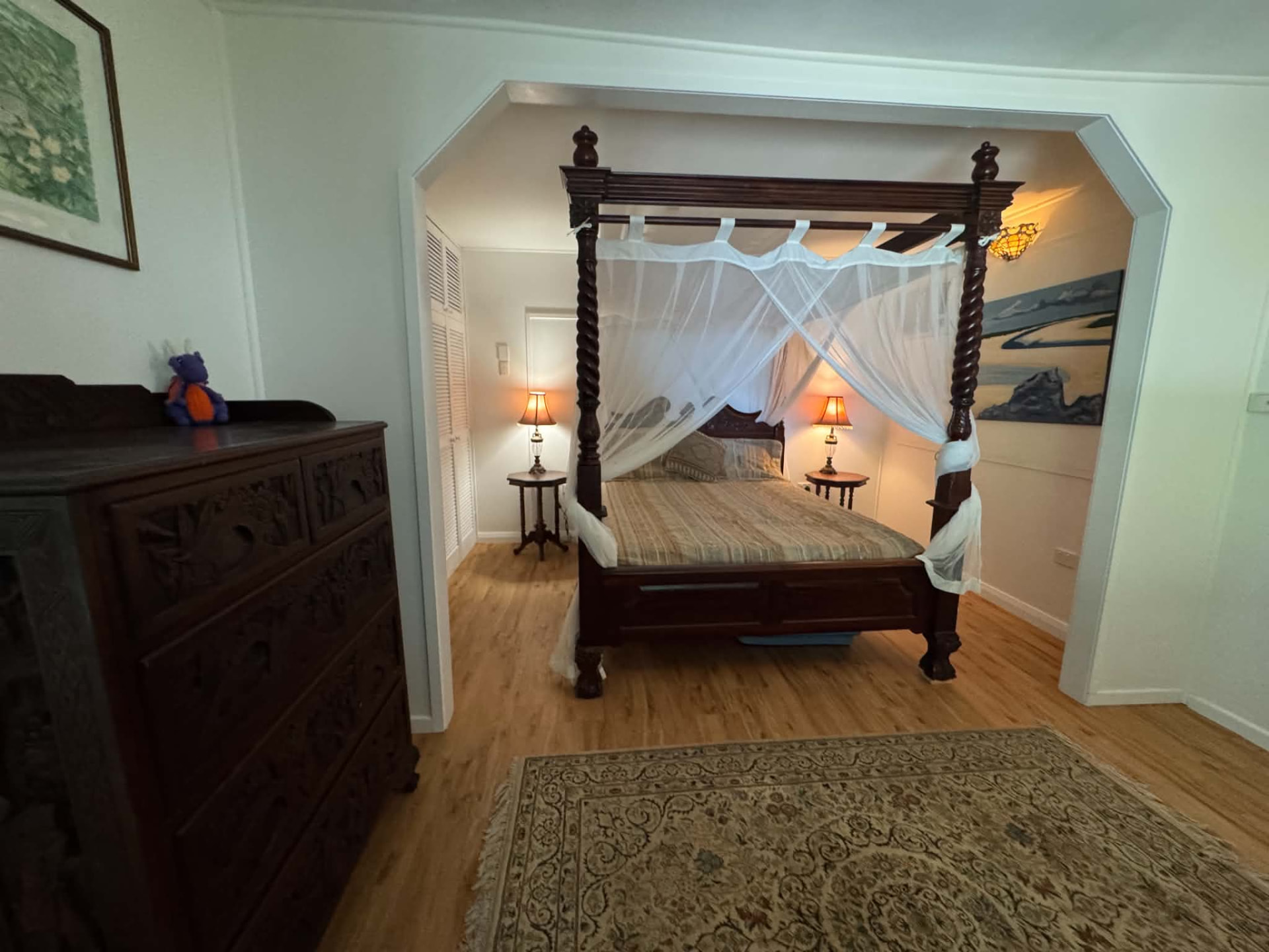 Four-poster bed with white mosquito-net drapes and carved timber details