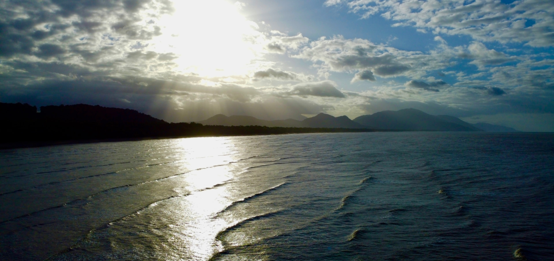 Aerial view of sunlight breaking over the rainforest coast and Coral Sea