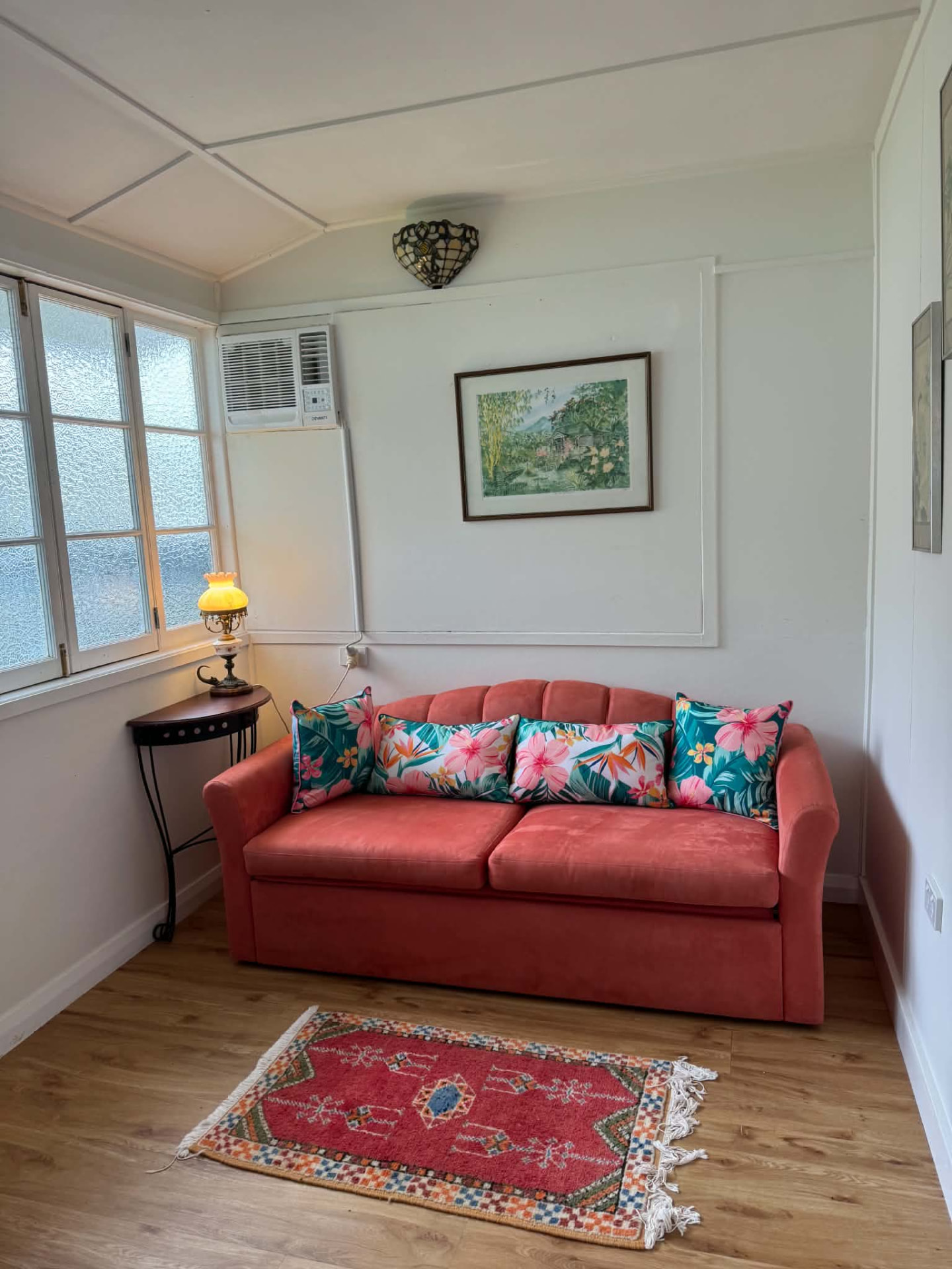 Coral sofa with tropical cushions and vintage lamp