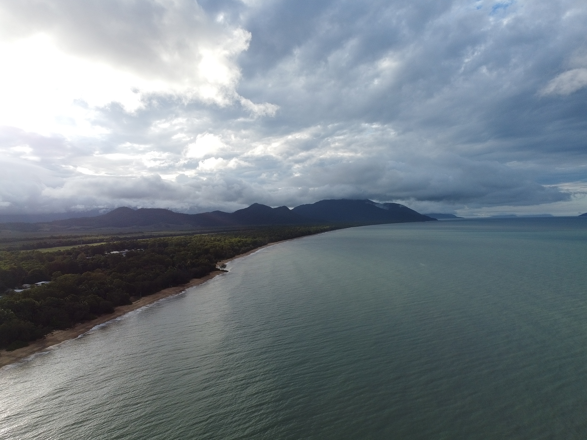 Aerial view of Bramston Beach coastline under dramatic clouds